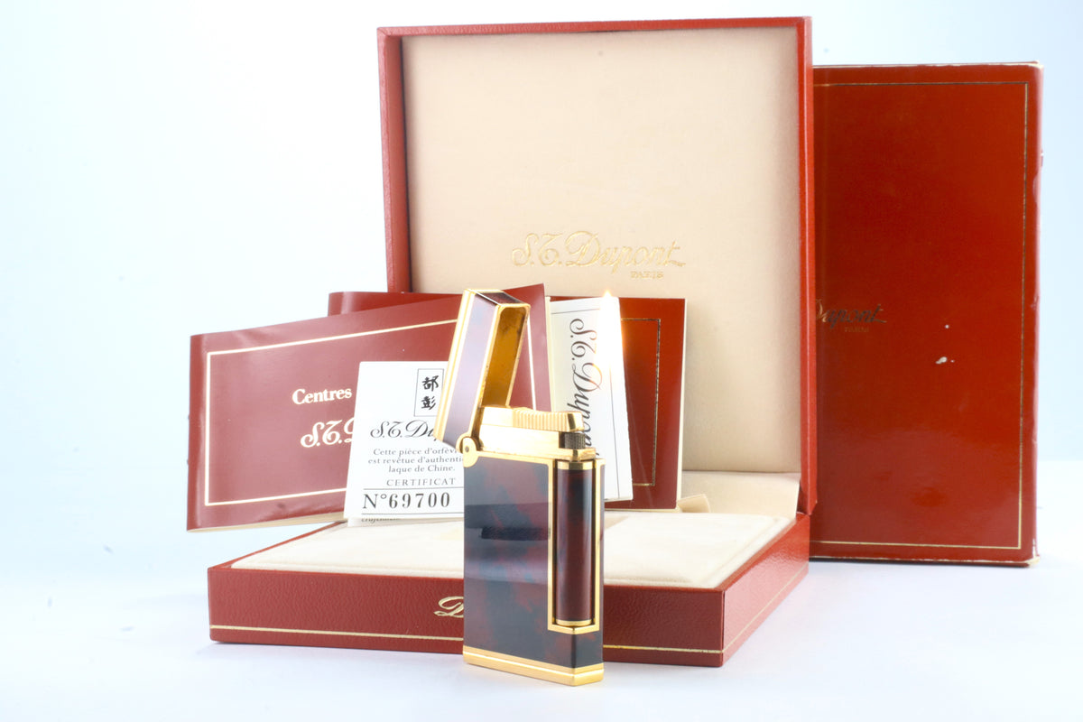 S.T. Dupont laque de Chine authenticity certificate number 69700, with the lacquer workshop seal, beside the red Centres S.T. Dupont booklet